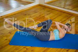 Fit woman doing stretching exercise on mat