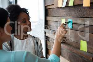 Female graphic designer writing on sticky notes