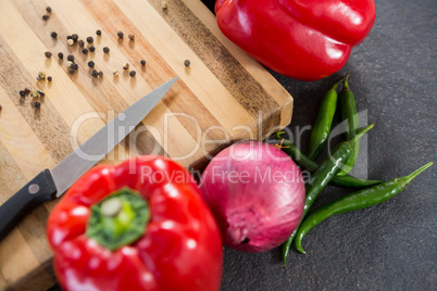 Bell pepper, onion, chillies and knife on wooden board