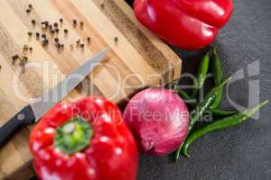 Bell pepper, onion, chillies and knife on wooden board
