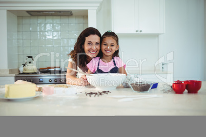 Portrait of mother and daughter standing in kitchen