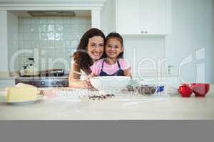 Portrait of mother and daughter standing in kitchen