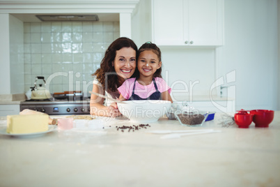 Portrait of mother and daughter standing in kitchen