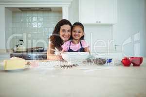 Portrait of mother and daughter standing in kitchen