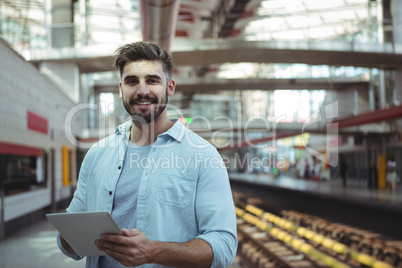 Smiling executive using digital tablet on platform