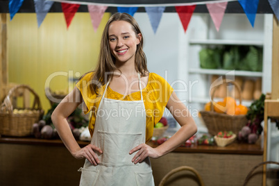 Smiling woman vendor standing in the grocery store with hands on hips