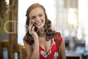 Portrait of smiling woman talking on mobile phone at counter