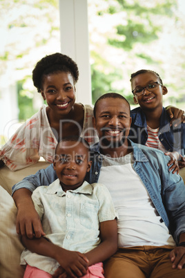 Portrait of parents and kids sitting on sofa in living room