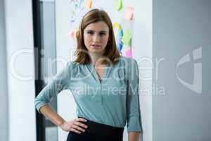 Female graphic designer standing with hand on hip in creative office