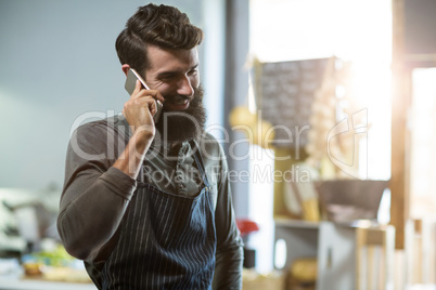 Salesman talking on mobile phone at counter
