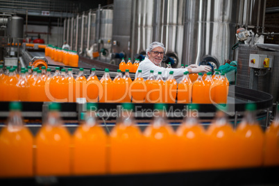 Factory engineer monitoring filled juice bottle on production line