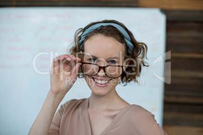 Smiling female executive holding spectacles in office