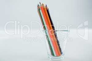 Colored pencils kept in glass on white background