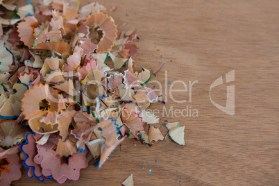 Colored pencils shavings on wooden background
