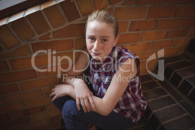Portrait of sad schoolgirl sitting alone on staircase