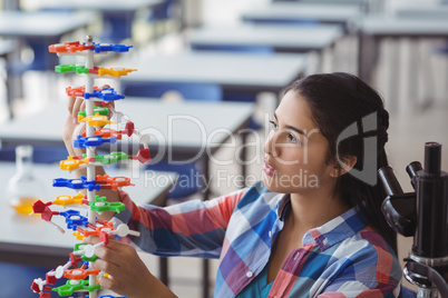 Attentive schoolgirl experimenting molecule model in laboratory