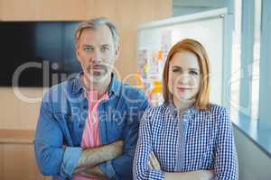 Portrait of male and female executives standing with arms crossed in conference room