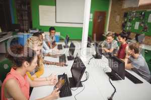Smiling students studying in computer classroom