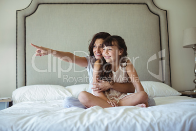 Mother with daughter pointing at a distance on bed