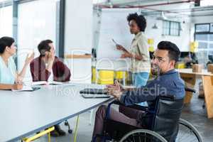Portrait of smiling disabled business executive in wheelchair at meeting