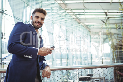 Smiling businessman using mobile phone at railway station