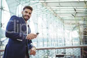 Smiling businessman using mobile phone at railway station