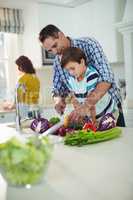 Father and son chopping vegetables in kitchen