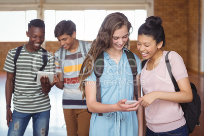 Happy students using mobile phone and digital tablet in campus