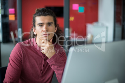 Male executive sitting with on chin in office