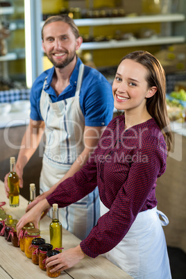 Shop assistants arranging jam and pickle jars at grocery shop