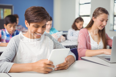 Students using digital tablet and laptop in classroom