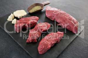 Beef steaks, spices and garlic on slate plate