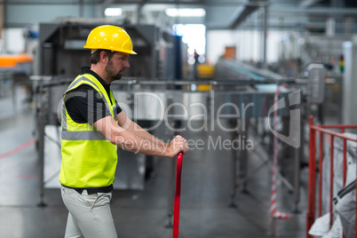 Factory worker pulling trolley in factory