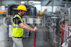 Factory worker pulling trolley in factory