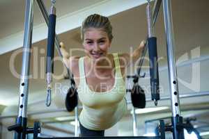 Portrait of beautiful woman performing stretching exercise on pilates cadillac