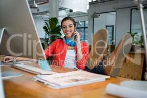 Smiling female graphic designer talking on mobile phone