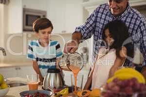 Father preparing smoothie with his kids in kitchen