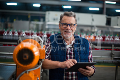 Portrait of smiling factory worker standing with a digital tablet in the factory