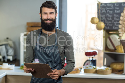 Portrait of salesman holding clipboard at counter