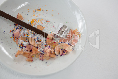 Colored shavings with brown color pencil and sharpener in saucer
