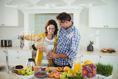 Happy couple preparing smoothie in kitchen