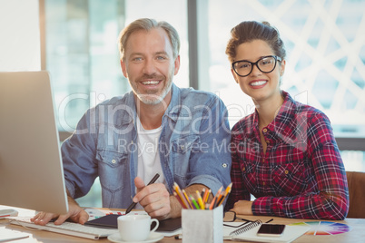 Portrait of male graphic designer sitting with coworker in office