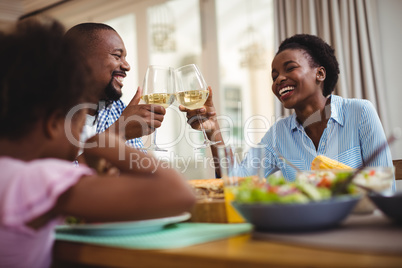 Family toasting glasses of wine while having meal on dining table