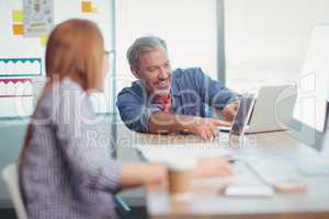 Male and female executive discussing over digital tablet