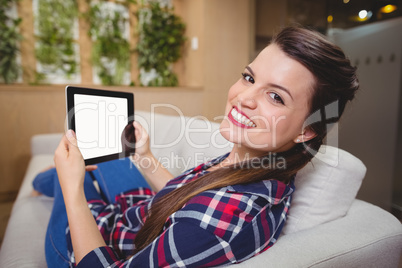 Portrait of female business executive relaxing on sofa and using digital tablet