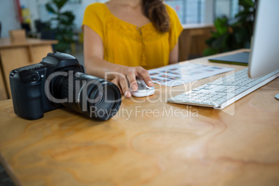 Digital camera kept of table and graphic designer working in background