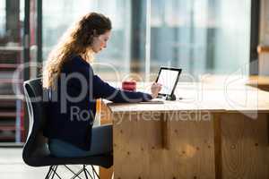 Female business executive using digital tablet at desk