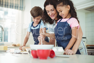 Mother and kids mixing the dough while preparing cookies