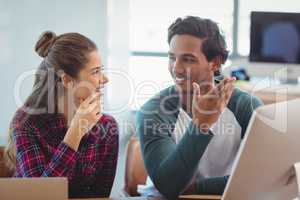 Male and female graphic designers interacting with each other at desk