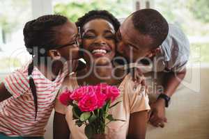 Man and daughter kissing woman on cheeks